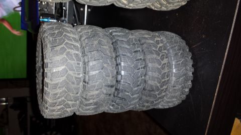 1993 Toyota 4Runner - A set of four aggressive tread off-road tires are displayed on a dark surface.