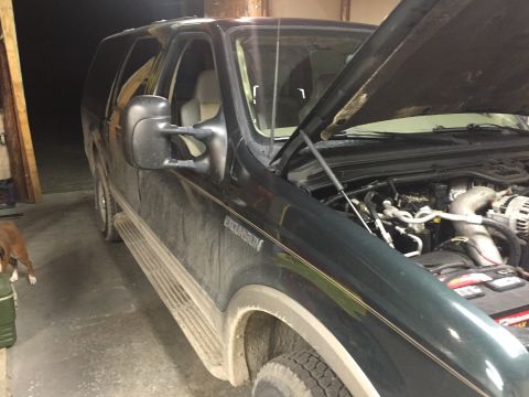 2003 Ford Excursion - The front of a dark green Ford Excursion is shown with the hood up, revealing the engine compartment.