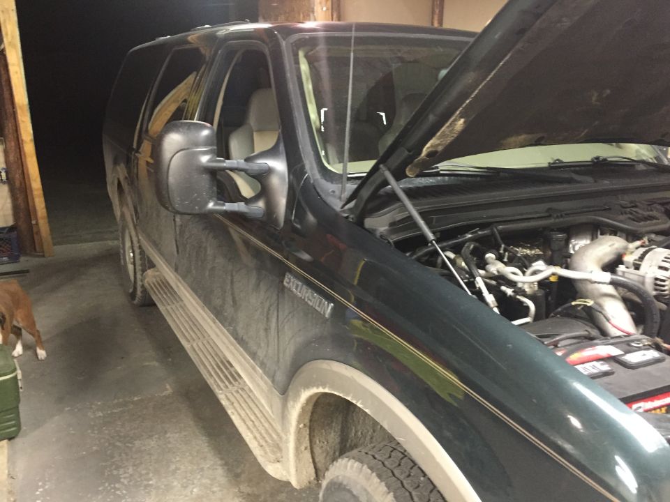 Dark green Ford Excursion with hood open showing engine bay. "EXCURSION" badge visible on fender