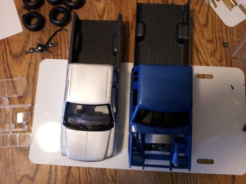 1995 Ford Bronco - Model truck parts and two assembled truck bodies are shown on a wooden surface.