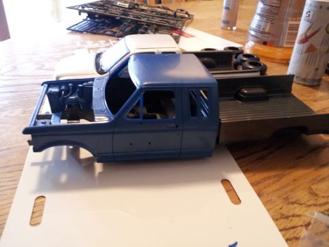 1995 Ford Bronco - Model truck parts are laid out on a wooden table, with a blue cab and chassis in the foreground.