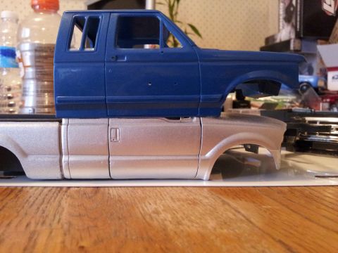 1995 Ford Bronco - Two unpainted model truck bodies are stacked, a blue cab on a silver lower body.