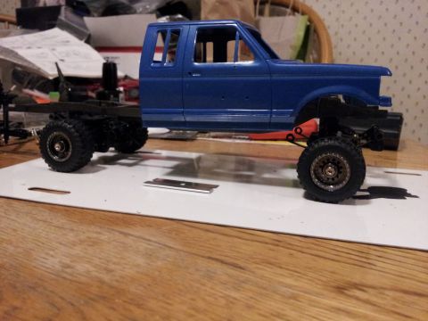 1995 Ford Bronco - Model truck chassis with a blue cab is assembled on a workbench.