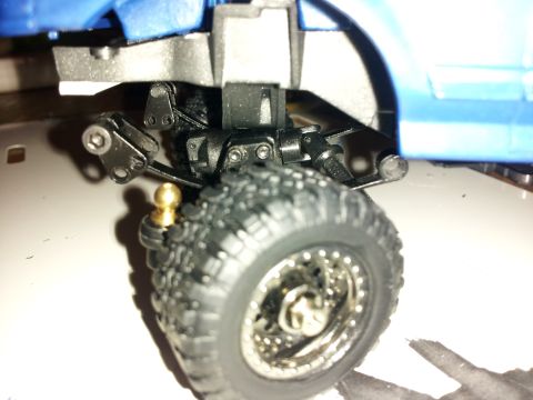 1995 Ford Bronco - Detail of a model truck's suspension system and off-road tire, a brass tow ball attachment.