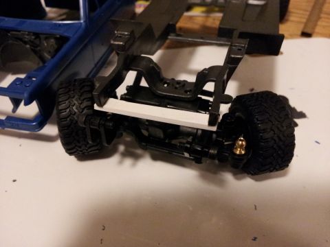 1995 Ford Bronco - Close-up of a model truck's chassis and suspension system, with a blue body section in the background.