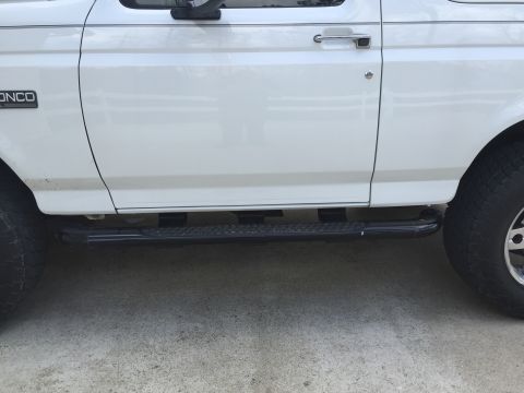 1995 Ford Bronco - Side view of a white 1995 Ford Bronco, highlighting its running boards and door handle.