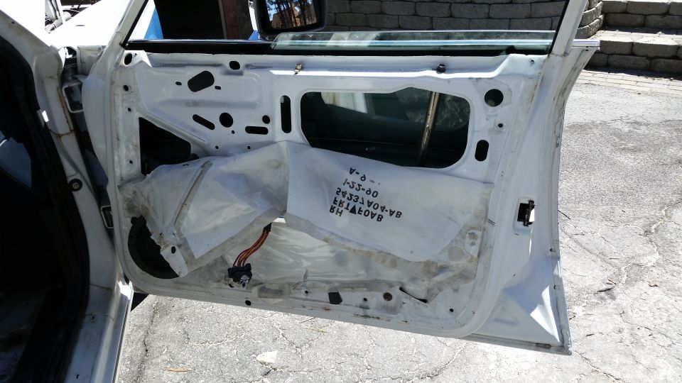 White car door interior with exposed insulation and wiring harness