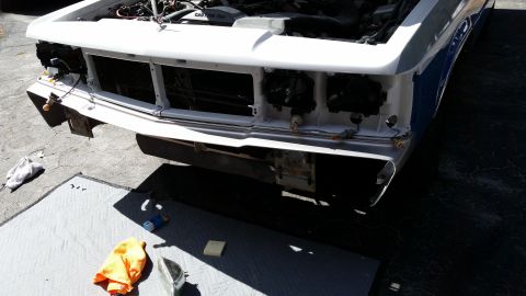 1991 Ford LTD Crown Victoria - The front end of a white car is disassembled, with the grille and headlights removed for repair or maintenance.
