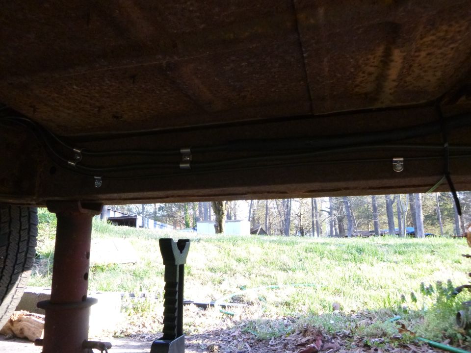 Underbody view of vehicle with brake lines, tire visible