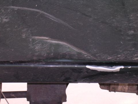 1985 Ford Bronco - Vehicle body panel shows damage and repair work with white filler material.