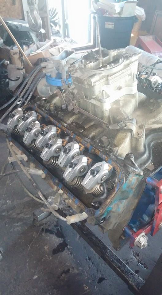 V8 engine block with carburetor, valve covers removed showing rocker arms