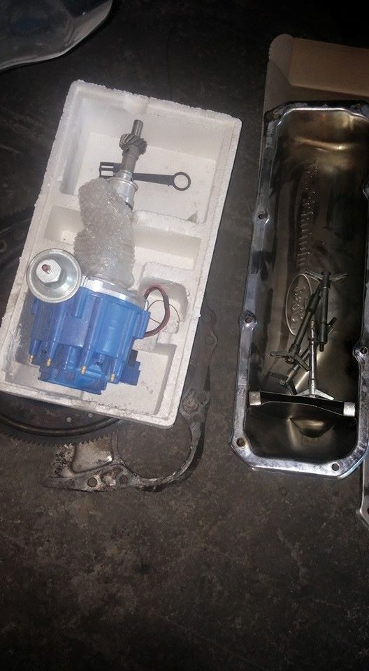 Blue distributor and oil pan with bolts on a dark surface