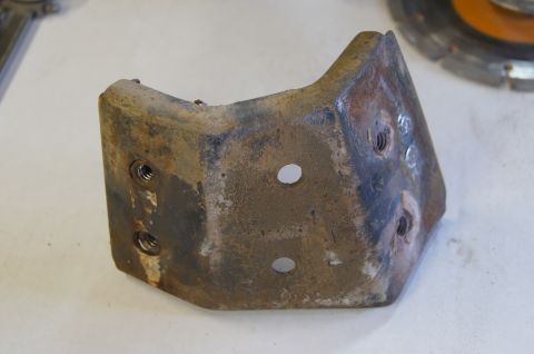 1979 Ford Bronco - A close-up view of a rusty metal bracket with several bolt holes and threaded inserts.
