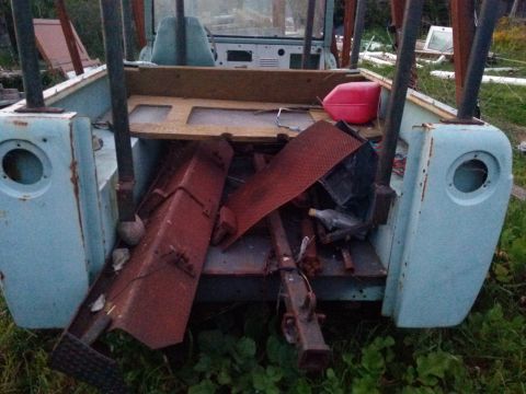 1991 Ford Bronco - The rear of a light blue SUV, filled with scrap metal and a red gas can, sits outdoors.