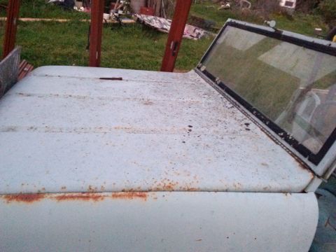 1991 Ford Bronco - Close-up of a weathered vehicle hood and windshield frame, showing signs of rust and wear.