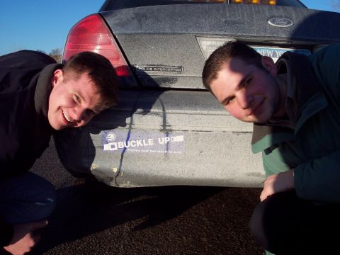2001 Ford Crown Victoria - Two men pose by the rear of a 2001 Ford Crown Victoria Police Interceptor, which displays a "Buckle Up" sticker.