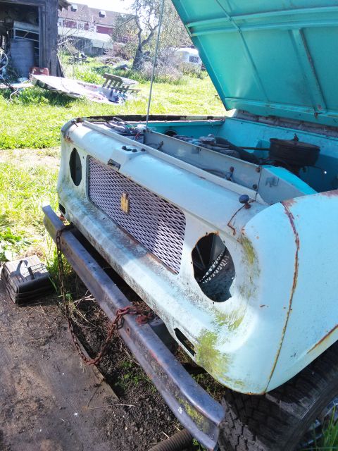 1991 Ford Bronco - Front view of a light blue International Harvester Scout with its hood open, revealing the engine compartment and a rusty bumper.