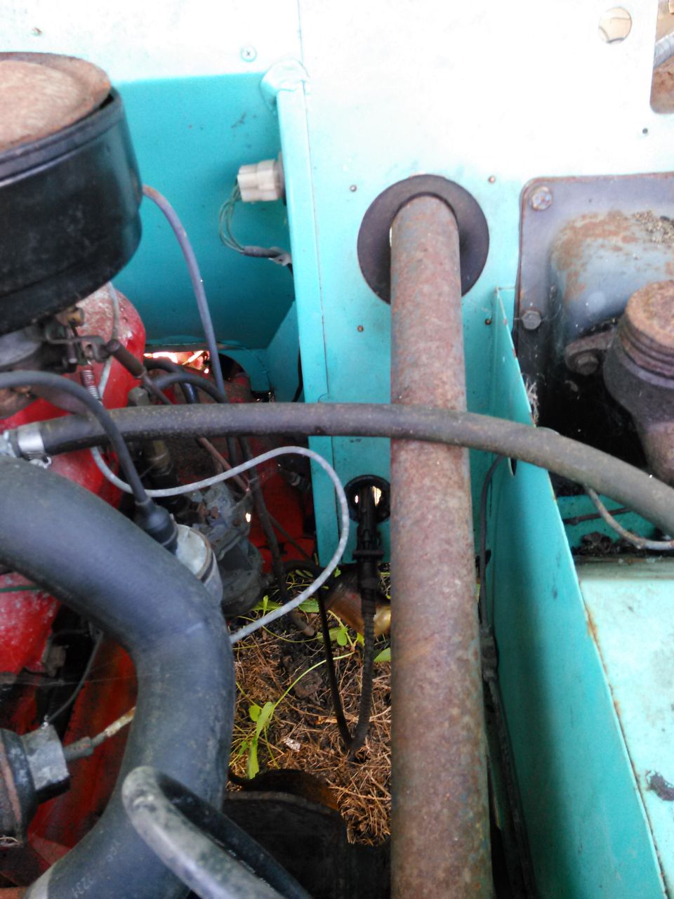 Engine bay detail showing exhaust pipe, red engine block, and turquoise paneling