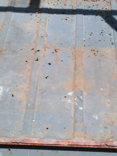 1991 Ford Bronco - The interior floor of a vehicle shows significant rust and wear, with distinct panel lines visible.