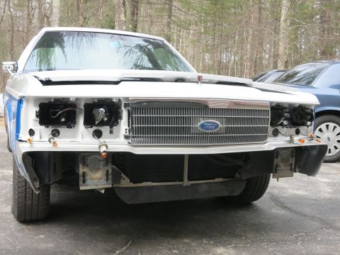 1991 Ford LTD Crown Victoria - Front view of a white Ford Crown Victoria with its front end disassembled, revealing exposed components.
