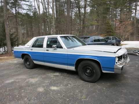 1991 Ford LTD Crown Victoria - Ford Crown Victoria sedan with two-tone paint, missing front grille, parked outside with another vehicle behind it.