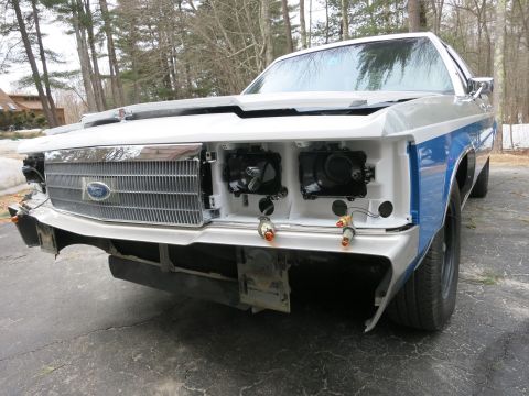 1991 Ford LTD Crown Victoria - The front end of a Ford Crown Victoria is shown with its grille and bumper removed, revealing the headlights and wiring.