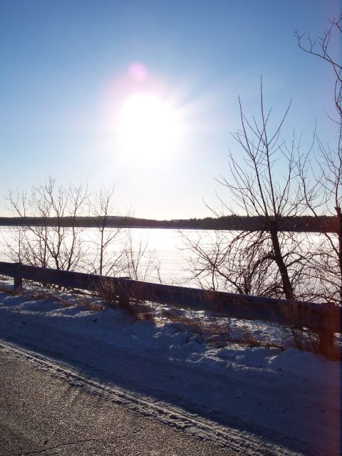 2001 Ford Crown Victoria - Winter scene with a bright sun over a frozen body of water and snow-covered ground.