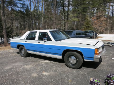 1991 Ford LTD Crown Victoria - A two-tone 1991 Ford Crown Victoria LTD sedan is parked outdoors with its hood open, showing two other vehicles in the background.