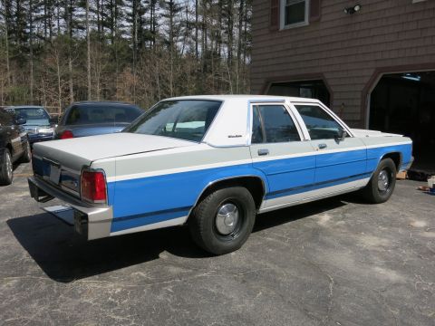 1991 Ford LTD Crown Victoria - A two-tone blue and white sedan is parked in front of a garage.