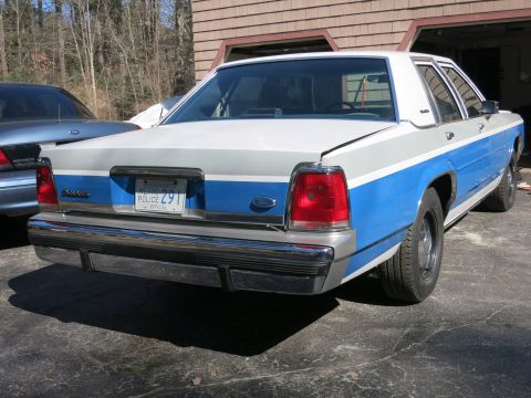1991 Ford LTD Crown Victoria - Rear view of a white and blue police car with "POLICE 291" on the license plate.