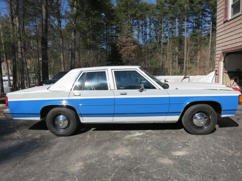 1991 Ford LTD Crown Victoria - This 1991 Ford Crown Victoria sedan is seen from the side, parked in a driveway with trees in the background.