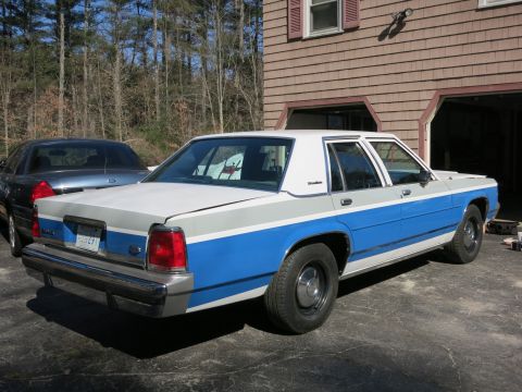 1991 Ford LTD Crown Victoria - A two-tone white and blue Ford Crown Victoria is parked in a driveway, with another dark sedan behind it.