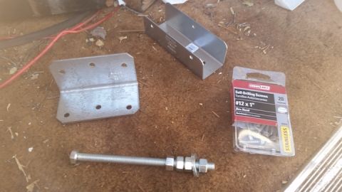 1985 Ford Bronco - Various metal brackets and fasteners are arranged on the floor, likely for vehicle installation.