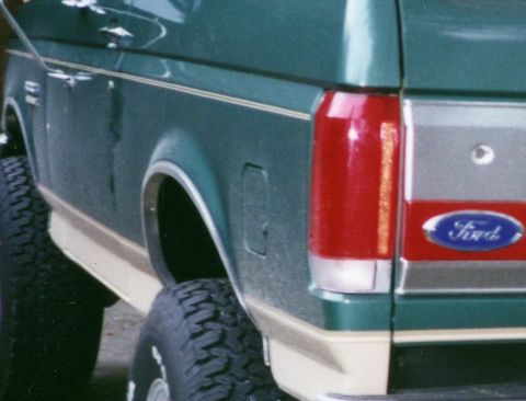 1990 Ford Bronco - Rear view of a green 1990 Ford Bronco, showing the quarter panel, taillight, and Ford emblem.
