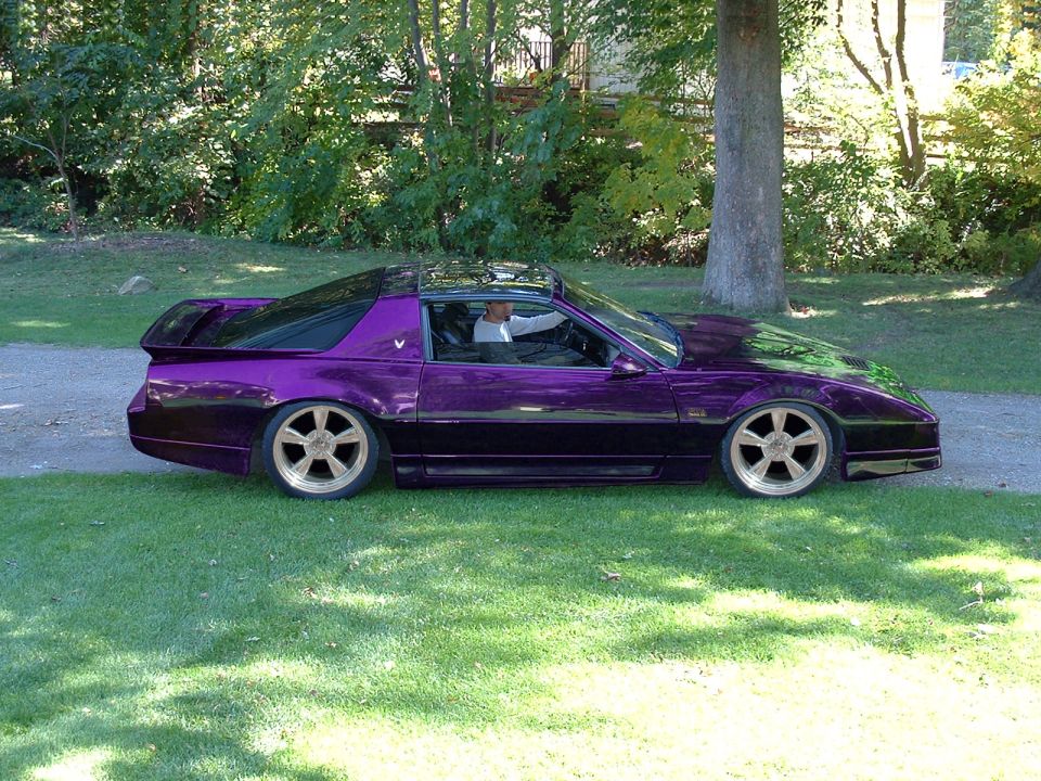 Lowered purple 1980s Ford Mustang Foxbody coupe parked on grass