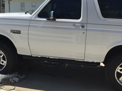 1995 Ford Bronco - Side view of a white 1995 Ford Bronco, showing its running boards and the 'BRONCO' badge.