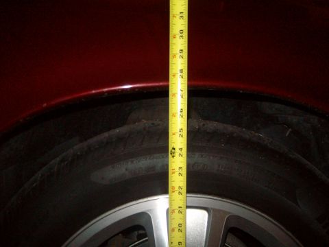 2004 Ford Crown Victoria - A tape measure is used to check the clearance above a vehicle's tire.