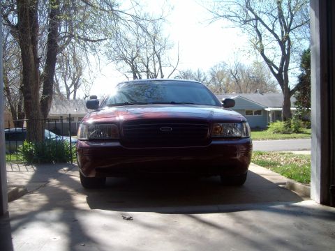 2004 Ford Crown Victoria - A dark red sedan is parked in a driveway, facing forward. The sun is shining brightly.