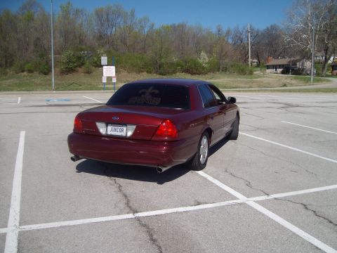 2004 Ford Crown Victoria - A red sedan is parked in a lot on a sunny day. The license plate reads JUNIOR.