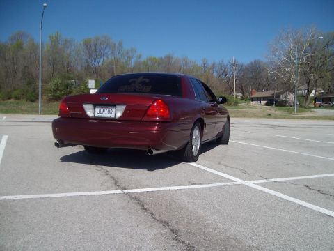 2004 Ford Crown Victoria - Maroon Ford Crown Victoria parked in a lot, rear view. License plate reads JUNIOR.