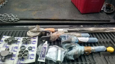 Yukon driveshaft parts and Super Joint Grease laid out on a truck bed. Includes U-joints and bearing caps