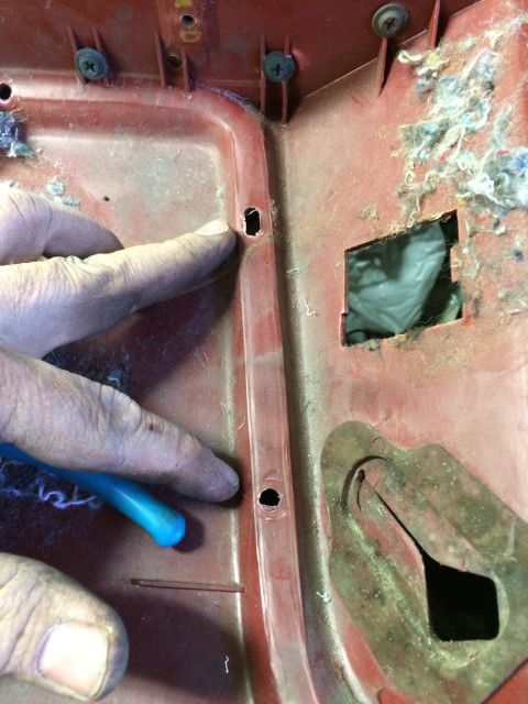 1986 Ford Bronco - A hand points to a red interior panel with visible damage and insulation material.