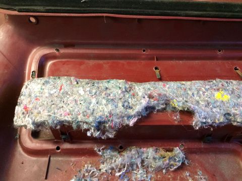 1986 Ford Bronco - Close-up of a red interior panel with frayed insulation and mounting hardware visible.