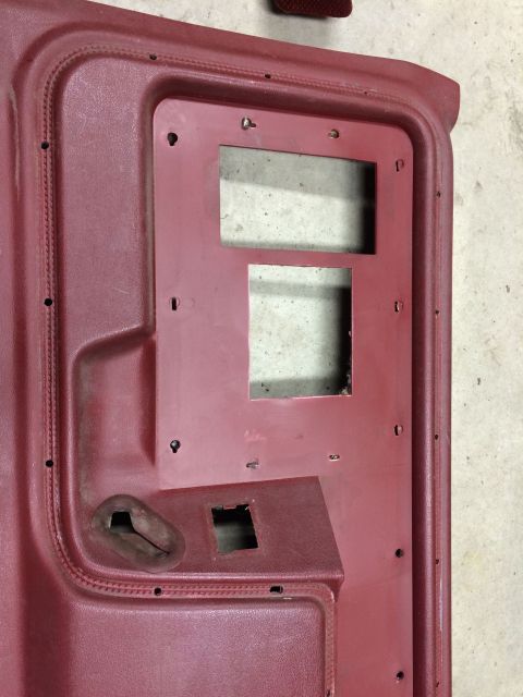 1986 Ford Bronco - Close-up of a red interior door panel, likely from a disassembled vehicle.