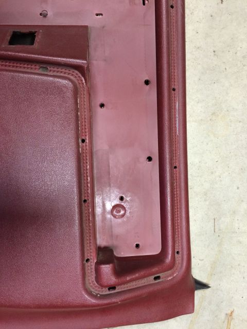 1986 Ford Bronco - Close-up of a disassembled car door panel, showing interior mounting points and textured trim.