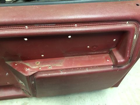 1986 Ford Bronco - Close-up of a disassembled car door panel, showing its interior construction and material.