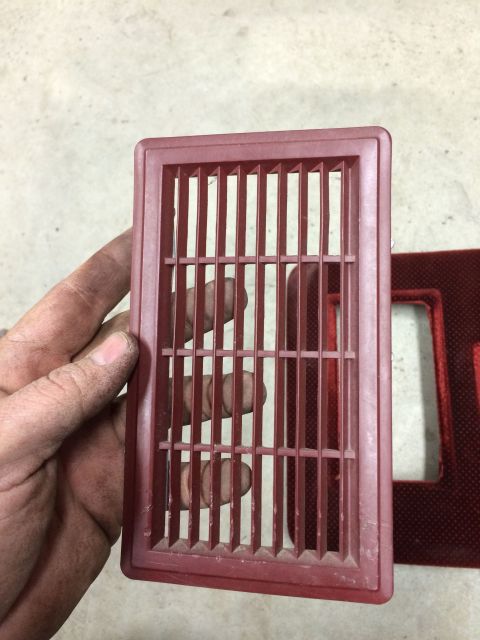 1986 Ford Bronco - A red plastic vent is held in a hand, with another part visible to the right.