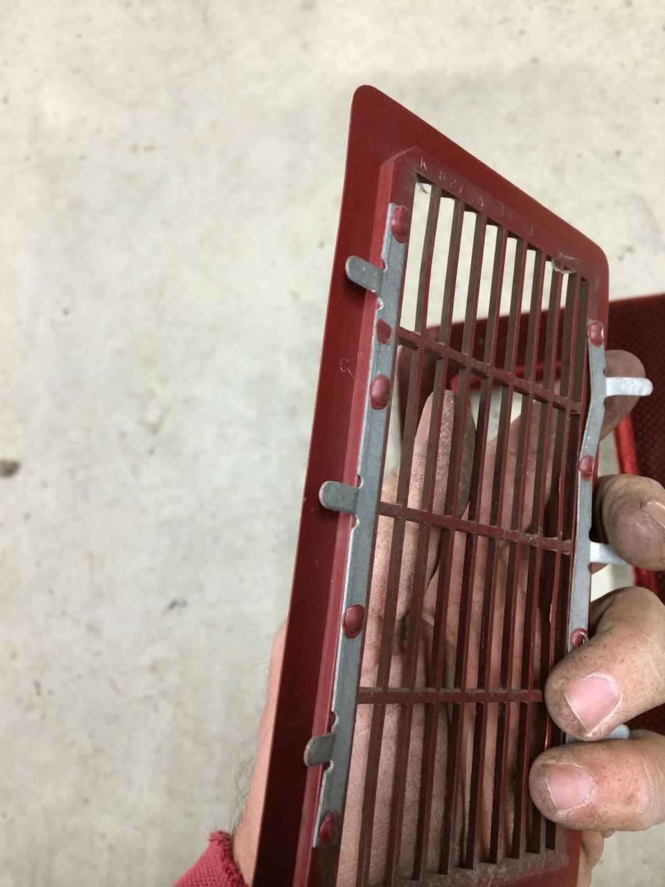 Red vent grille with metal bars held by a hand