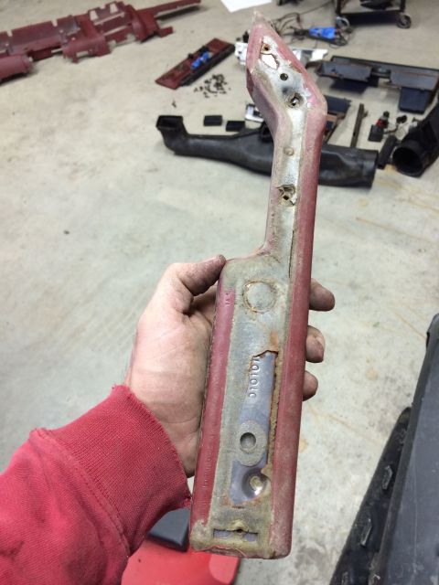 1986 Ford Bronco - A red interior car part, possibly from a disassembled vehicle, is held up for inspection. A part number is visible on the metal backing.