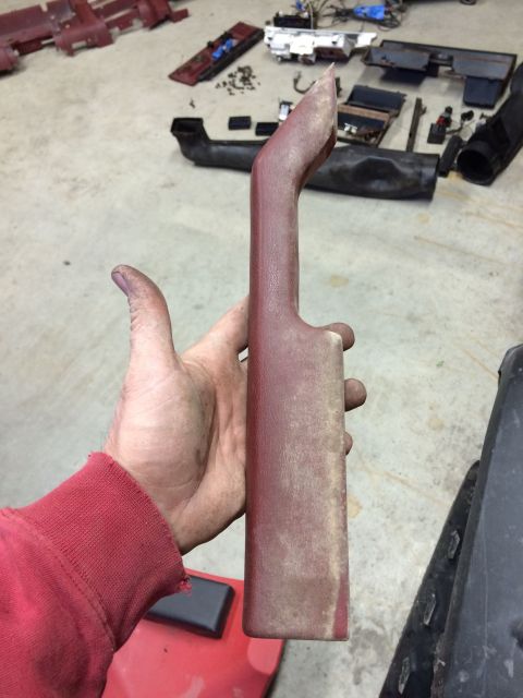 1986 Ford Bronco - Disassembled interior trim part held in hand, with other parts on the floor.